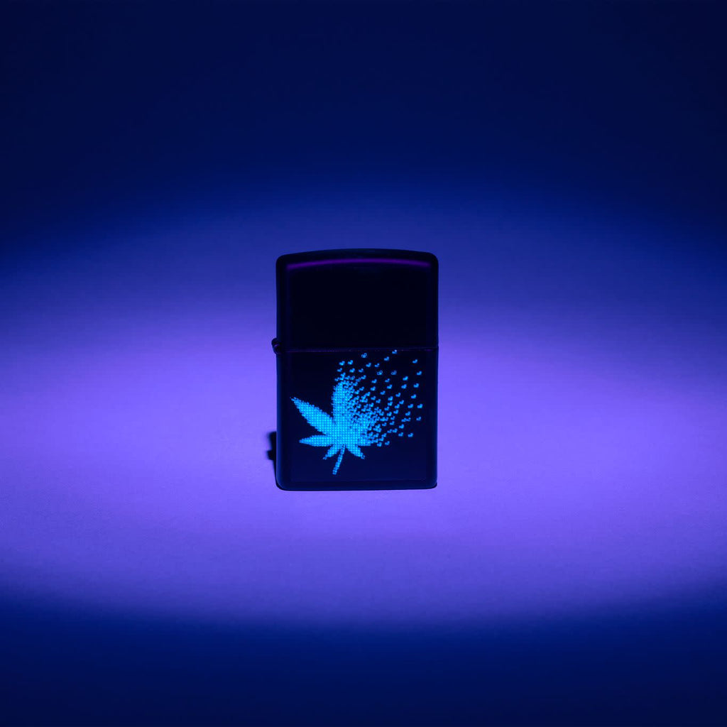 Lifestyle image of Zippo Black Light Pixel Cannabis Design Black Matte Windproof Lighter with the black light design glowing.