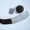 Lifestyle image of the NHL Winnipeg JetsT Street Chrome Windproof Lighter laying on ice with a hockey puck and stick
