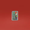 Lifestyle image of Zippo Freaky Nature Design Brushed Chrome Windproof Lighter standing in a red scene.