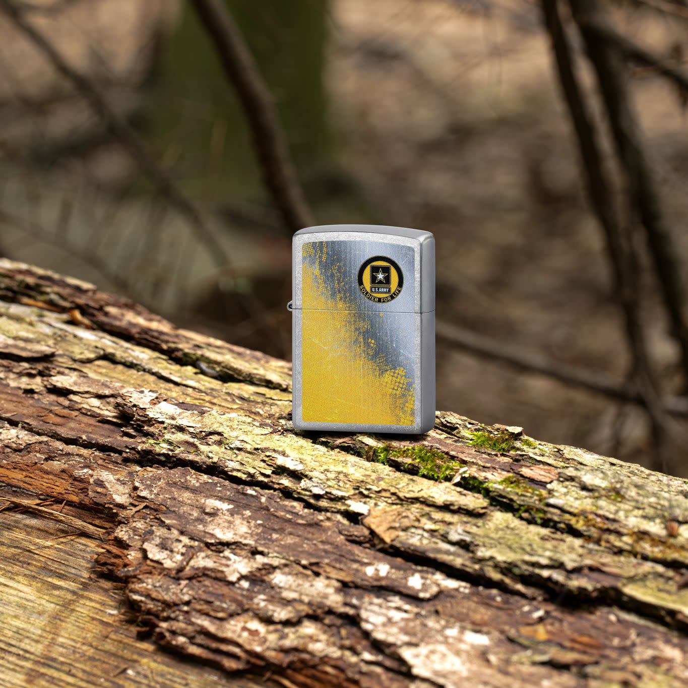 Lifestyle image of Zippo U.S. ArmyÂ® Soldier for Life Street Chrome Windproof Lighter standing on a log with branches in the background.