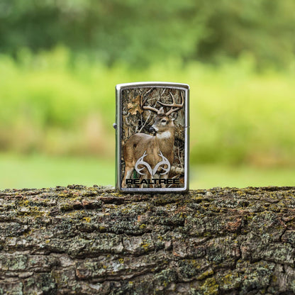 Lifestyle image of Zippo RealtreeÂ® Buck Design Street Chrome Windproof Lighter standing on a tree limb.