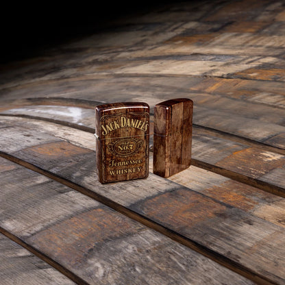 Lifestyle image of Zippo Jack Daniel'sÂ® Barrel Design 540 Tumbled Brass Windproof Lighter standing on a barrel.