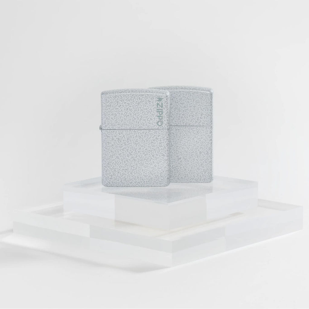 Lifestyle image of two Zippo Classic Glacier Logo Windproof Lighters on a clear pedestal and a white background.