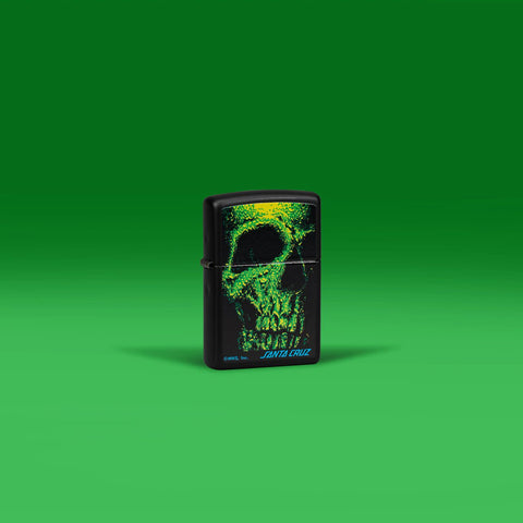Lifestyle image of Zippo Santa Cruz Skull Design Black Matte Windproof Lighter standing in a green scene.