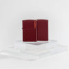 Lifestyle image of two Zippo Classic Merlot Logo Windproof Lighters on a clear pedestal with a white background.