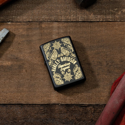 Lifestyle image of Zippo Harley-DavidsonÂ® American Legend Black Matte Windproof Lighter laying on a piece of wood with a screwdriver and pliers next to it.
