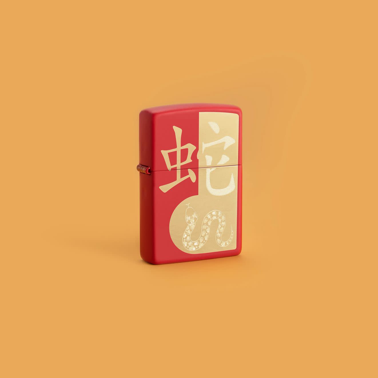 Lifestyle image of Zippo Year of the Snake 2025 Red Matte Windproof Lighter on a yellow-orange background.