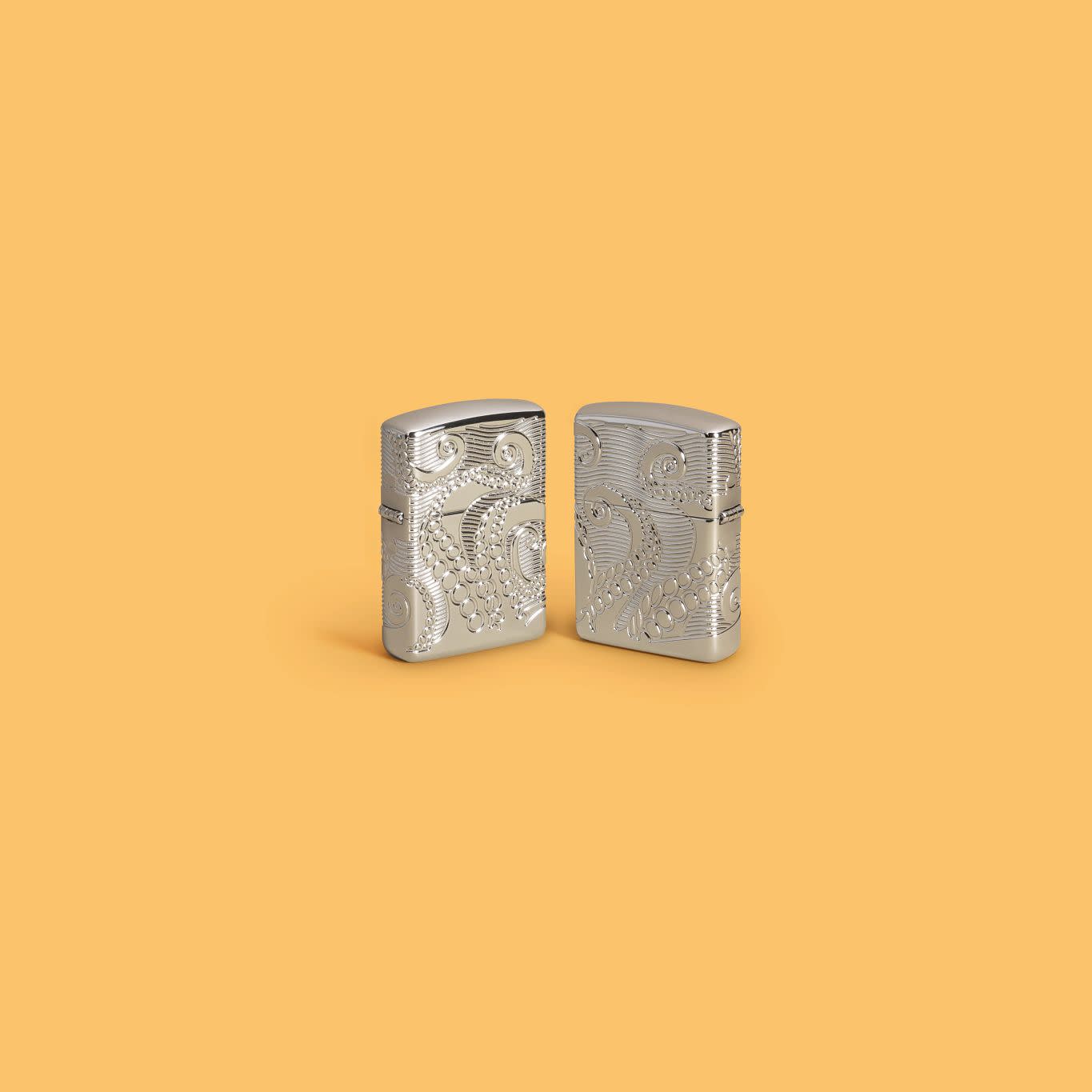 Lifestyle image of two Zippo Tentacles Design ArmorÂ® High Polish Chrome Windproof Lighters on a light orange background.