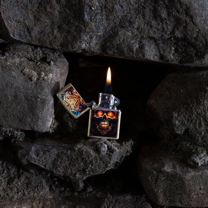 Lifestyle image of Zippo Stained Glass Skull Design Street Brass Windproof Lighter open and lit inside an opening within a stack of rocks.