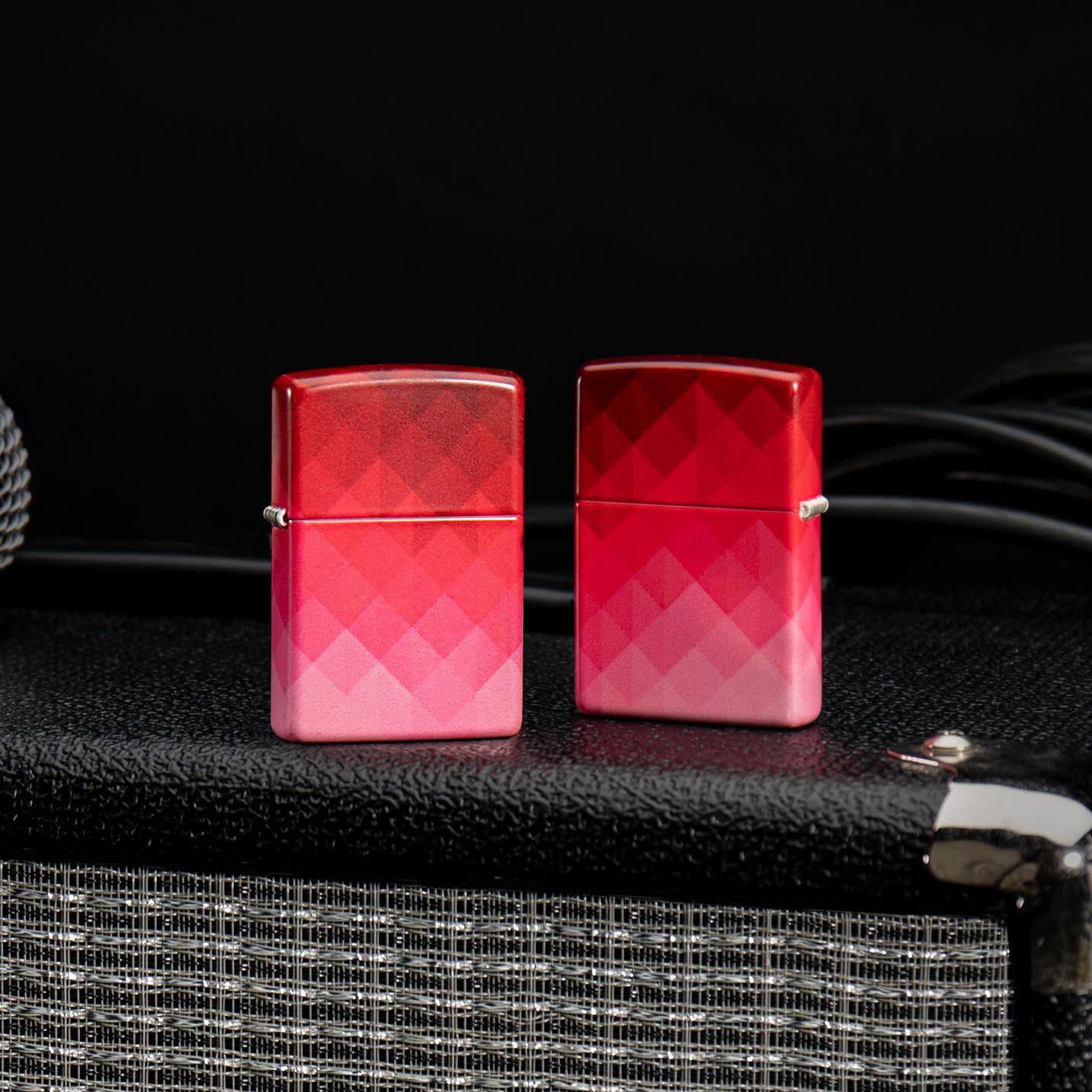 Lifestyle image of two Zippo Ombre Pixel Design 540 Matte Windproof Lighters standing on a speaker.
