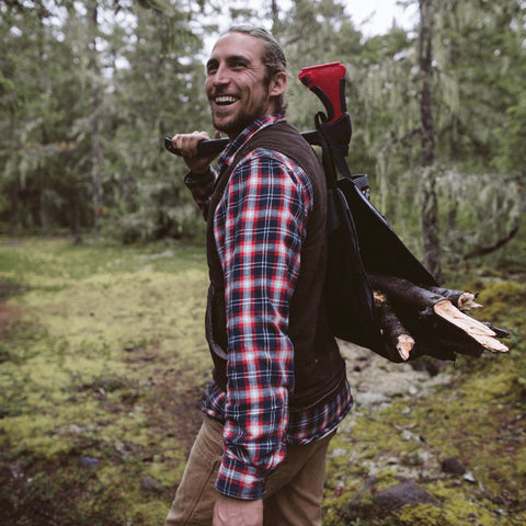 Lifestyle image of man in the woods carrying wood with the AxeSaw