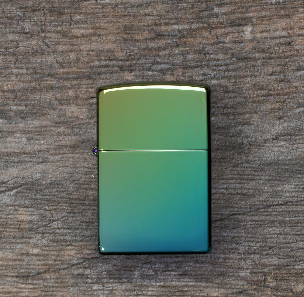 Lifestyle image of High Polish Teal Windproof Lighter laying flat on a wooden surface