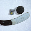 Lifestyle image of the NHL® Pittsburgh Penguins® Street Chrome™ Windproof Lighter laying on ice with a hockey puck and stick