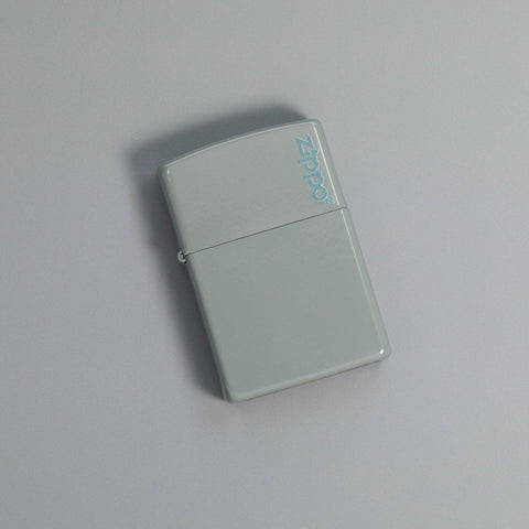 Lifestyle image of Classic Flat Grey Zippo Logo Windproof Lighter laying on a grey surface