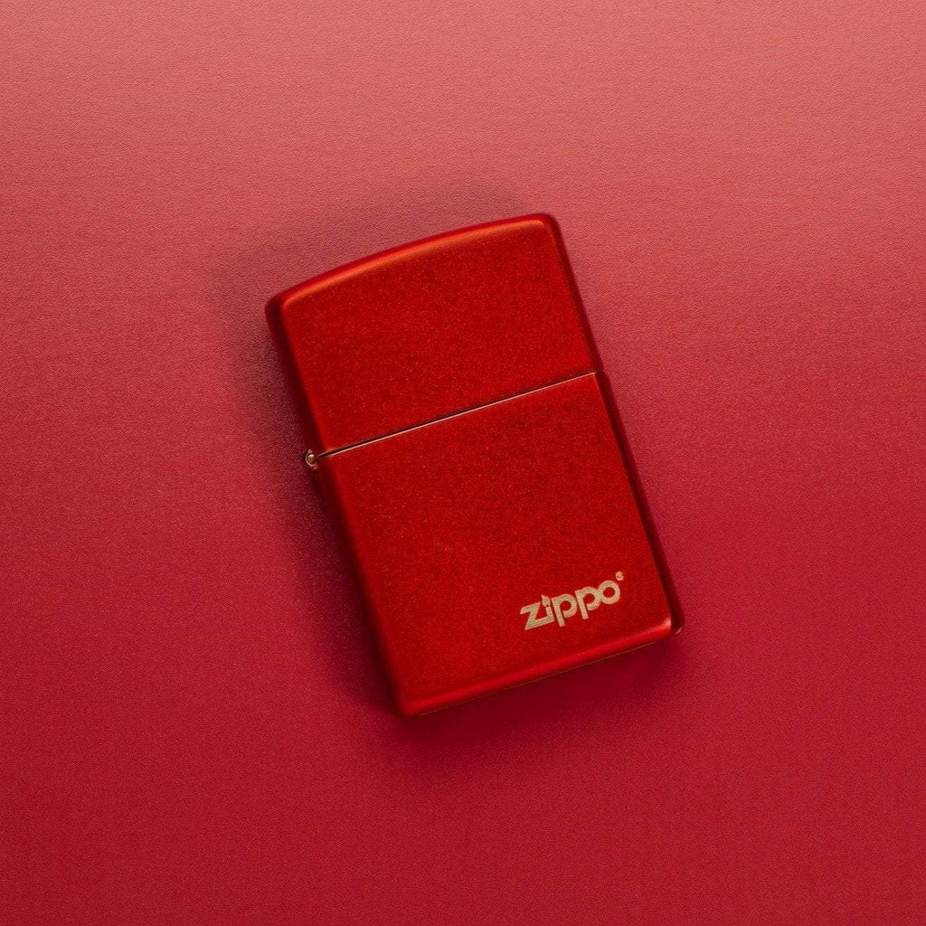 Lifestyle image of Classic Metallic Red Matte Zippo Logo Windproof Lighter laying on a red surface