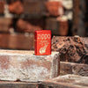 Lifestyle image of Zippo Retro Design Metallic Red Windproof Lighter standing on a brick