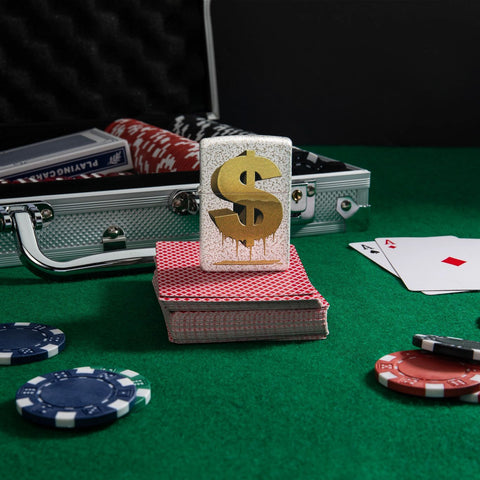 Lifestyle image of Drippy Dollar Design Mercury Glass Windproof Lighter standing on a deck of cards on a poker table, with poker chips scattered around.