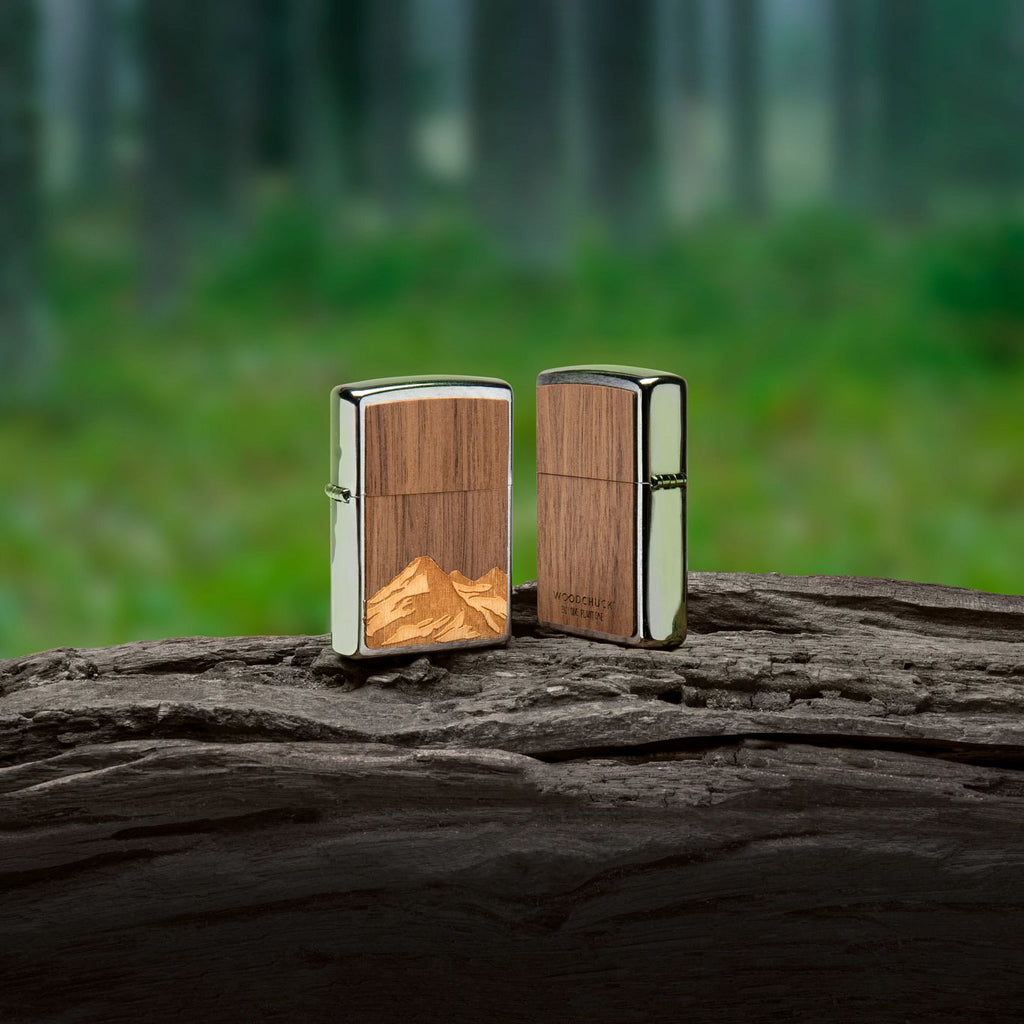Lifestyle image of WOODCHUCK USA Mountains Brushed Chrome Windproof Lighter, standing in a forrest.