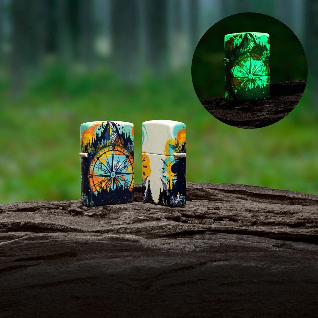 Lifestyle image of two Compass Design 540 Color Glow In The Dark Windproof Lighter standing on a log. In the top right corner there is an image of the lighter glowing in the dark.