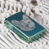 Lifestyle image of French Bulldog Design High Polish Green Windproof Lighter laying on a blanket