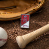 Lifestyle image of MLB® Los Angeles Angels™ Street Chrome™ Windproof Lighter laying on a baseball field with a glove, ball, and bat.