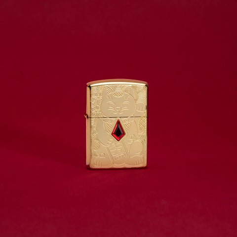 Lifestyle image of Lucky Cat Design Emblem Attached Armor® High Polish Brass Windproof Lighter standing in a red scene.