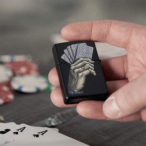 GIF of Dead Mans Hand Design Black Matte Windproof Lighter being flipped around in a mans hand, in front of a poker table