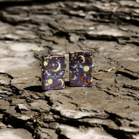 Lifestyle image of two Butterfly Skull Design 540 Color Windproof Lighters standing on a rock.