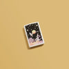 Lifestyle image of Frank Frazetta Fairy Spaceship White Matte Windproof Lighter laying on a yellow background.