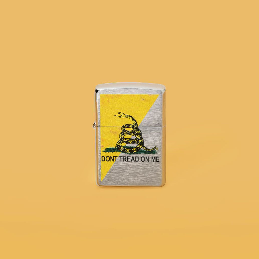 Lifestyle image of Dont Tread On Me Flag Design Street Chrome™ Windproof Lighter standing in a yellow background.
