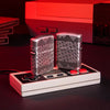 Lifestyle image of two Gaming Cheat Code Armor® Antique Silver Windproof Lighters standing on a vintage gaming controller with a retro gaming system in the background. One lighter is showing the front of the design with the other showing the back.
