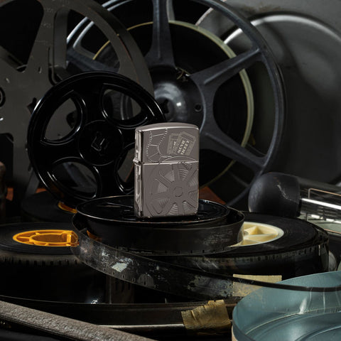 Lifestyle image of Celebrating Movies Armor® Black Ice® Windproof Lighter standing on film with film reels in the background.