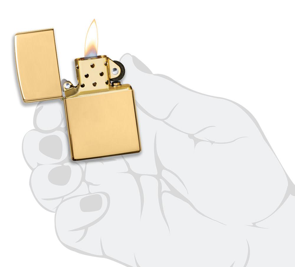 ArmorÂ® High Polish 18K Solid Gold Windproof Lighter lit in hand.
