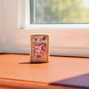 Lifestyle image of Literary Anatomy Flat Sand Windproof Lighter standing on a window sill with sun shining in