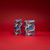 Lifestyle image of two Kimono Design 540 Color Windproof Lighters standing in a red background.