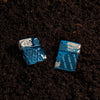 Lifestyle image of Skull Design Armor® High Polish Blue Windproof Lighter laying in the dirt.