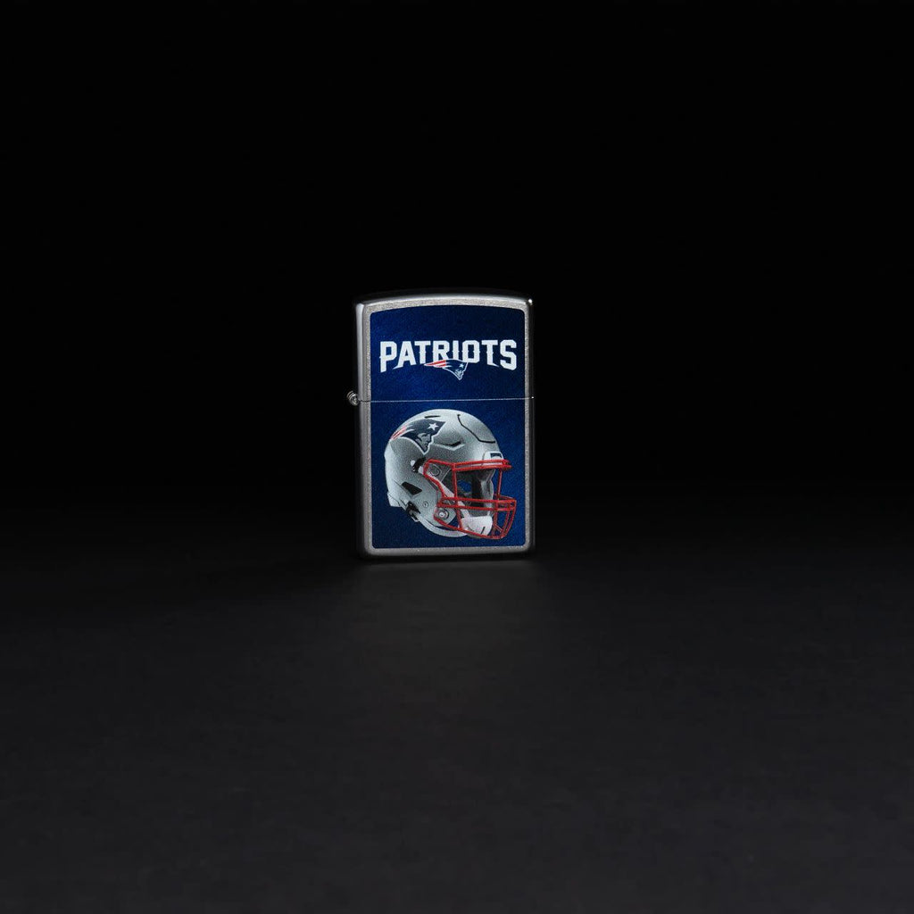 Lifestyle image of NFL New England Patriots Helmet Street Chrome Windproof Lighter standing in a black background.