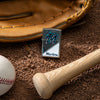 Lifestyle image of MLB™ Miami Marlins™ Street Chrome™ Windproof Lighter laying on a baseball field with a glove, ball, and bat.