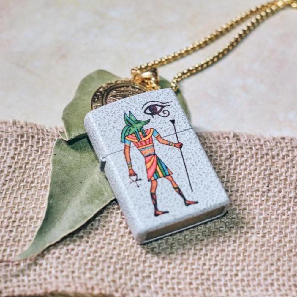 Lifestyle image of Anubis Design Mercury Glass Windproof Lighter laying down on leaf and necklace
