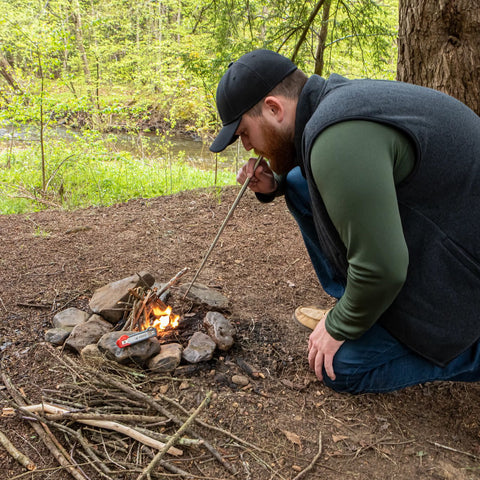 Lifestyle image of man using the collapsible manual bellows to add oxygen to the fire to get it roaring