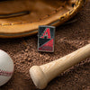 Lifestyle image of MLB® Arizona Diamondbacks™ Street Chrome™ Windproof Lighter laying on a baseball field with a glove, ball, and bat.