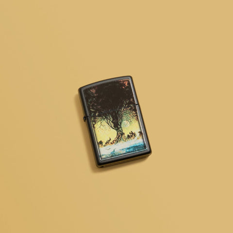 Lifestyle image of Frank Frazetta Tree Design Black Matte Windproof Lighter laying on a yellow background.