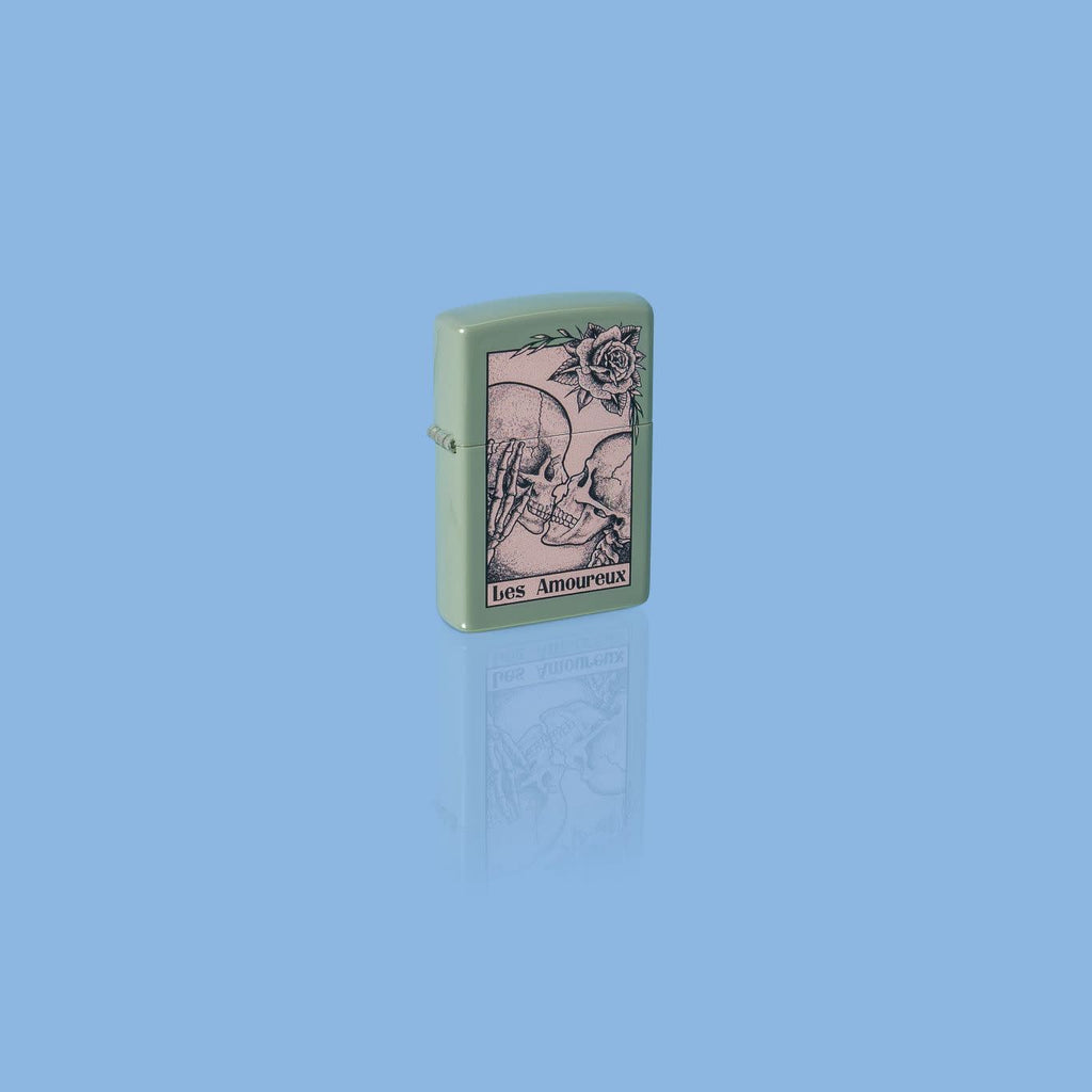 Glamour shot of Zippo Death Kiss Design Sage Windproof Lighter standing in a blue scene.