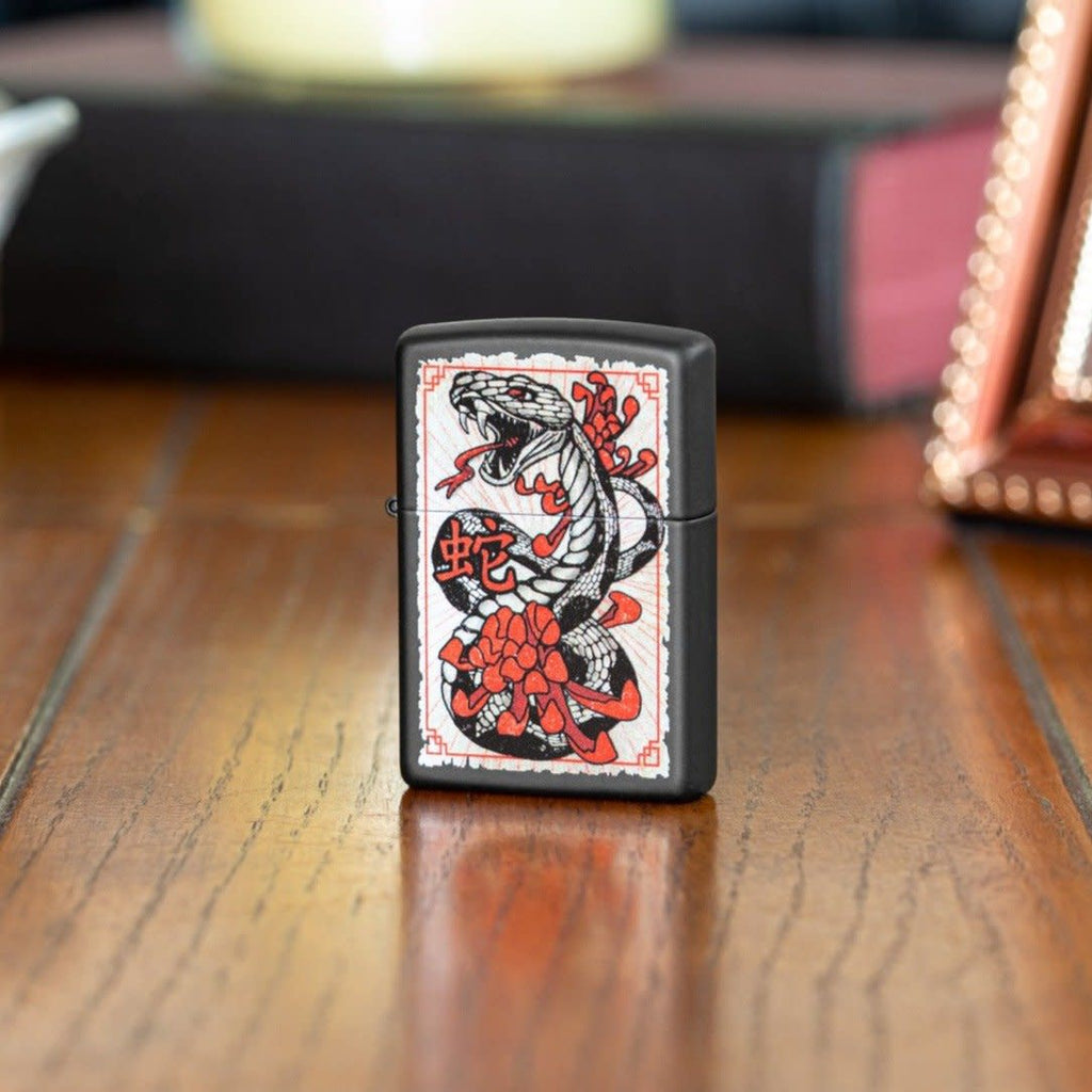 Lifestyle shot of Snake Tattoo Black Matte Windproof Lighter standing on a side stand