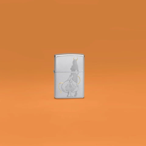 Lifestyle image of Zippo Devilish Ace Design Satin Chrome Windproof Lighter standing in an orange scene.