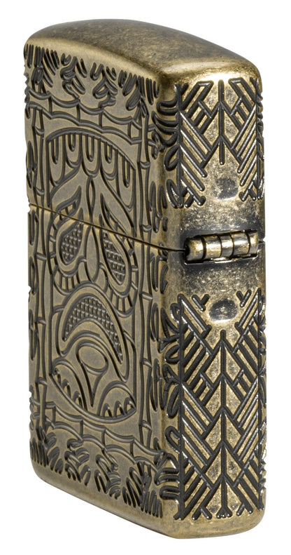 Tiki Design ArmorÂ® Antique Brass Windproof Lighter standing at an angle, showing the back and hinge side of the lighter.