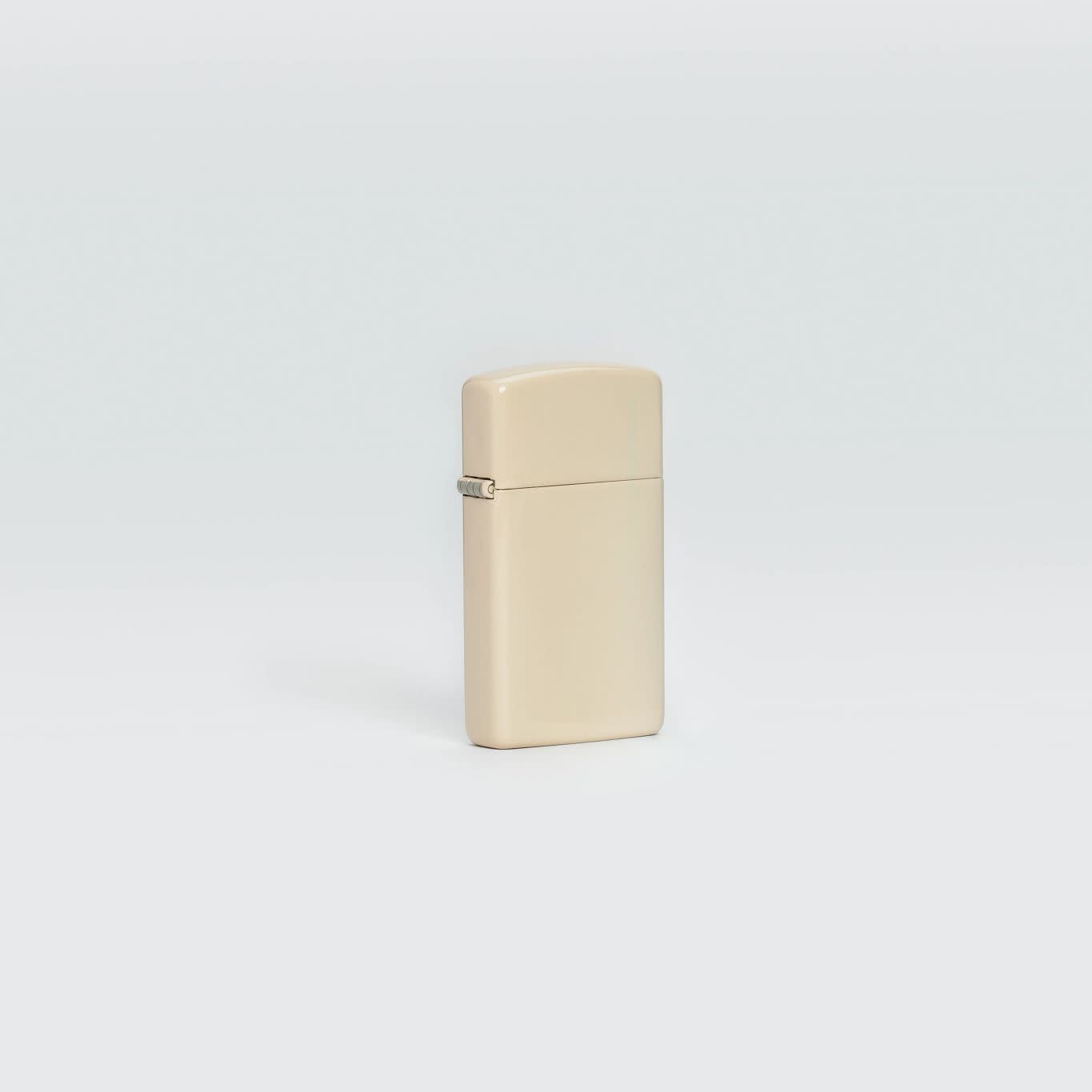 Lifestyle image of SlimÂ® Flat Sand Zippo Logo Windproof Lighter standing in a grey scene.