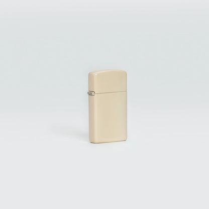 Lifestyle image of SlimÂ® Flat Sand Zippo Logo Windproof Lighter standing in a grey scene.