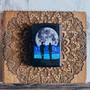 Front shot of Moon Couple Design Iridescent Windproof Lighter laying on a wooden mandala background
