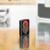 Lifestyle shot of Zippo Crow Tattoo Design Black Matte Windproof Lighter standing in on a reflective table with tattoo equipment.
